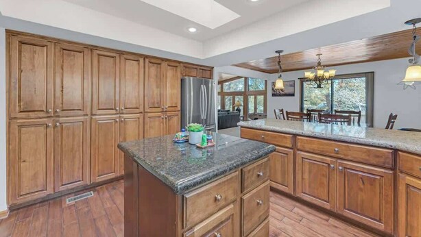A spacious kitchen with wooden cabinets, a granite countertop, and a large island. - Country Club Home with a Hot Tub (Flagstaff)