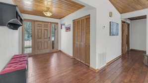 A spacious hallway with wooden flooring, a bench, and a ceiling with wooden beams. - Country Club Home with a Hot Tub (Flagstaff)