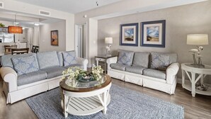 Ein Wohnzimmer mit zwei Sofas, einem Couchtisch und einem Essbereich mit einer Chandelier.