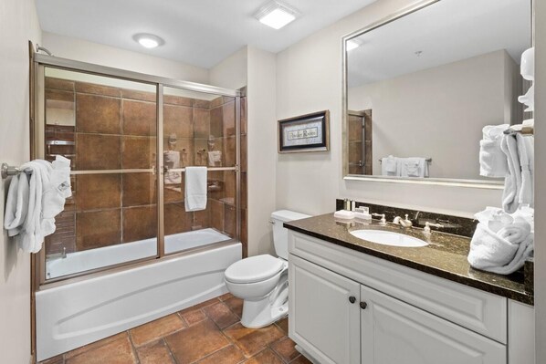 A modern bathroom with a glass-enclosed shower, a white toilet, a sink with a vanity, and a large mirror.