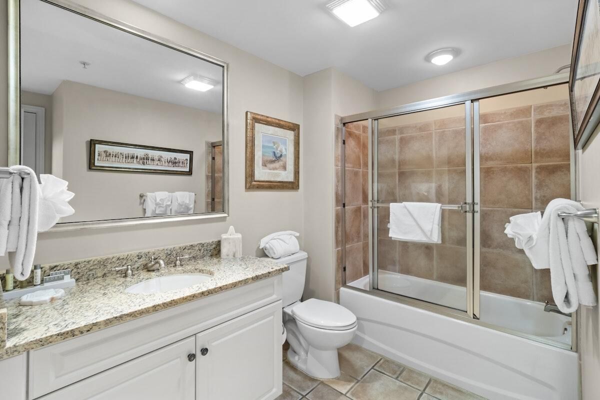A bathroom with a sink, toilet, and shower area.