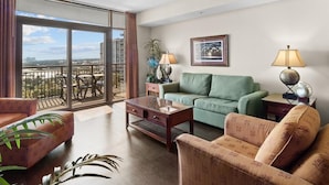 A spacious living room with a balcony, a green sofa, a wooden coffee table, and a patterned armchair. - Sunset Symphony Luxurious 2BR/2BA Oceanfront Condo (North Myrtle Beach)