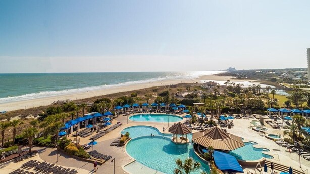 A resort with multiple swimming pools, beach access, and lounge areas. - Sunset Symphony Luxurious 2BR/2BA Oceanfront Condo (North Myrtle Beach)