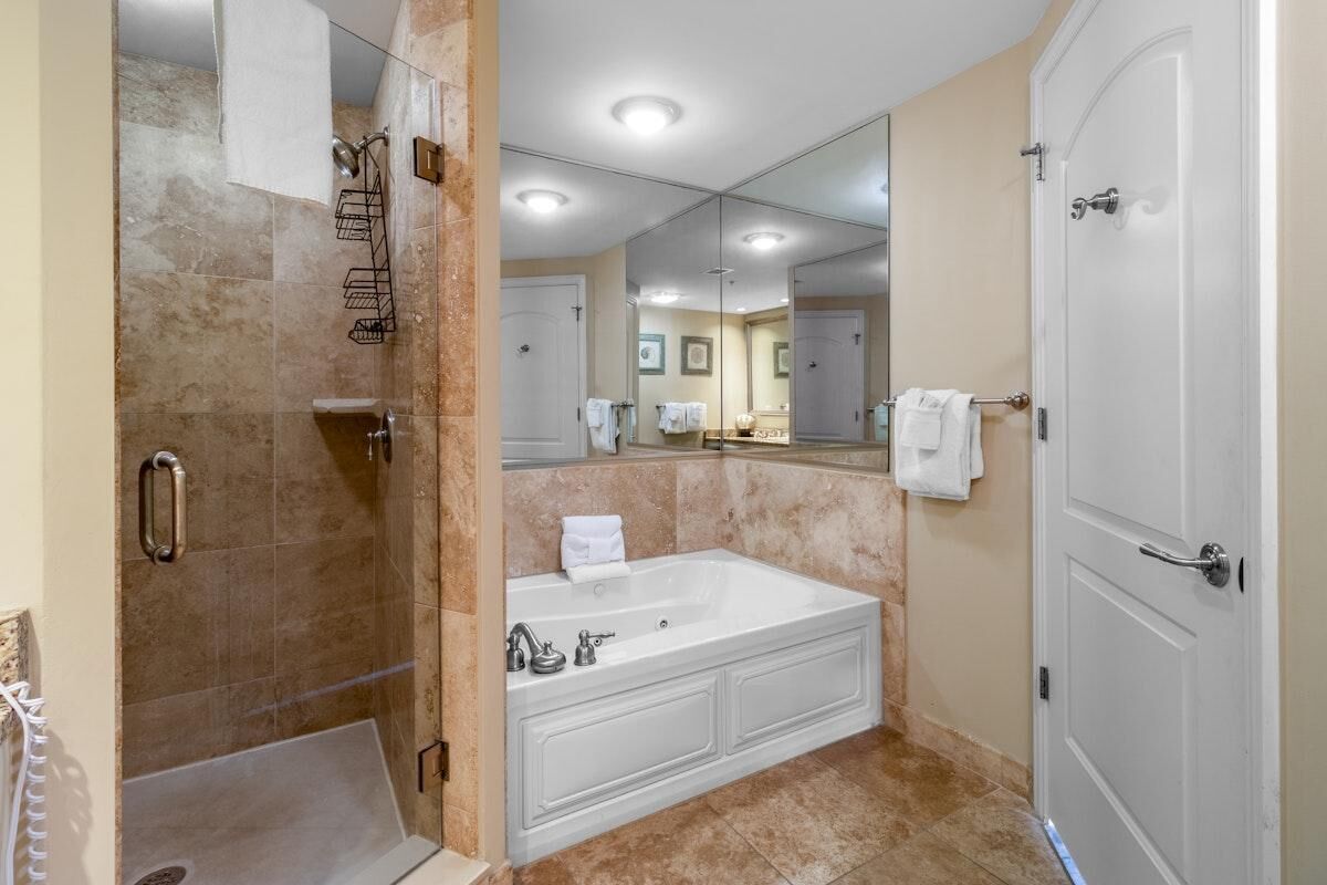 A modern bathroom with a walk-in shower, a large bathtub, and a full-length mirror.
