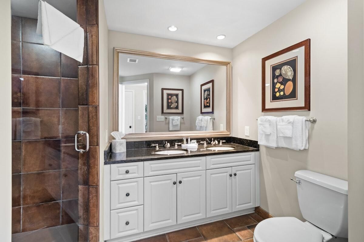Une salle de bain avec un meuble-lavabo à deux vasques, un grand miroir et des toilettes.
