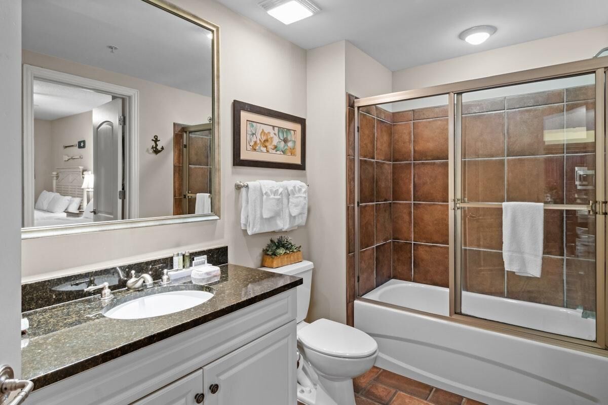 Un baño con lavamanos, inodoro y ducha con mampara de vidrio.