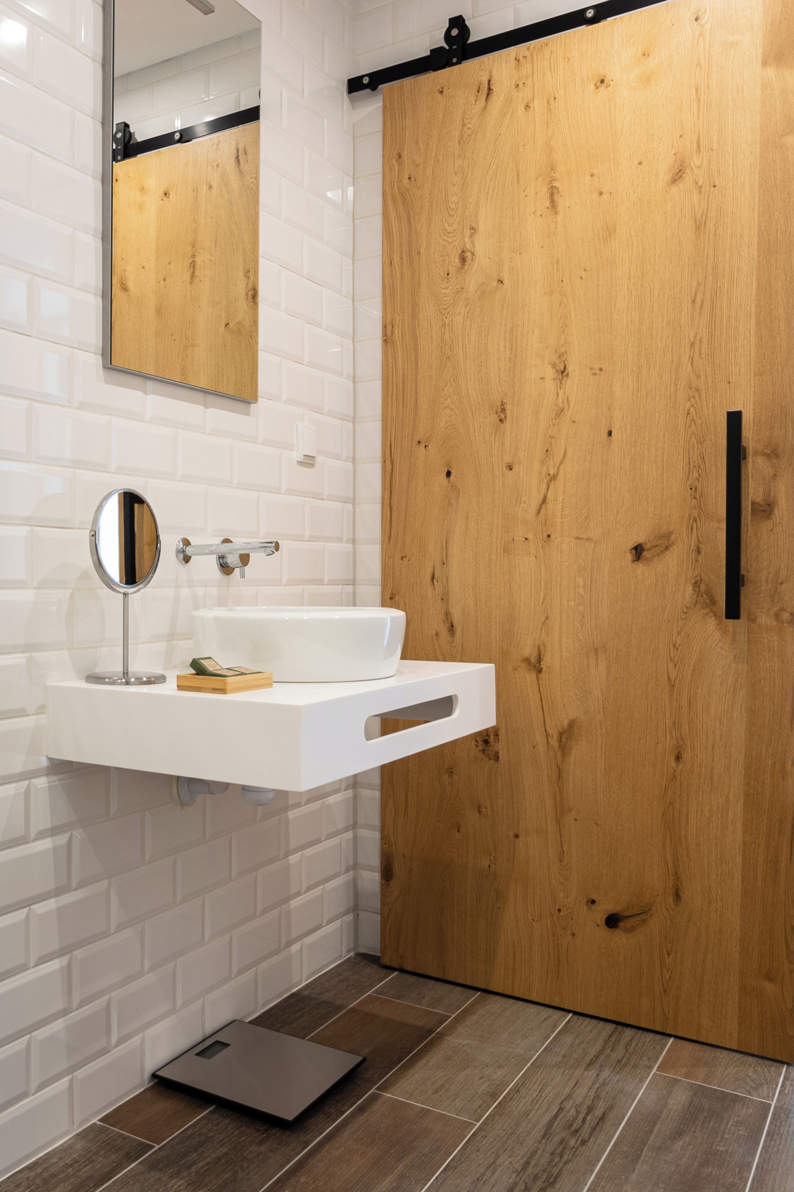 Kylpyhuone, jossa on valkoinen pesuallas, peili ja puinen ovi.