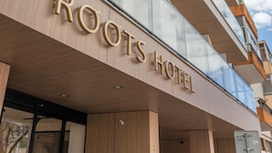 A hotel with a modern design, featuring a prominent "ROOTS HOTEL" sign on the facade.
