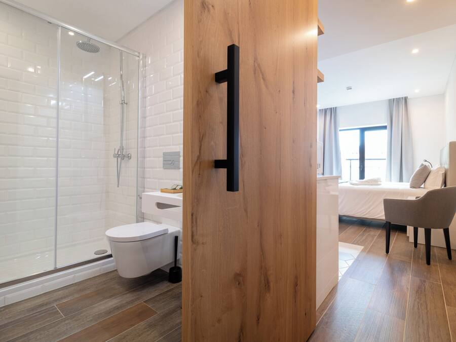 Un baño moderno con cabina de ducha de vidrio, inodoro blanco y puerta de madera.