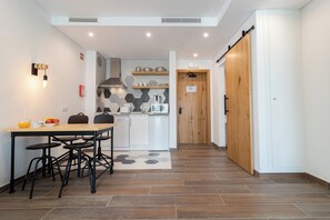 A modern kitchen with white cabinets, a wooden door, and a dining area with a table and chairs.