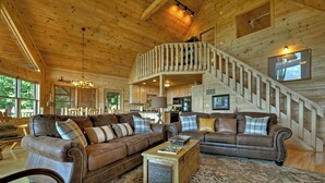 Ein geräumiges Wohnzimmer mit hohen Decken, Holzwänden und einer Treppe, die zu einer oberen Ebene führt.