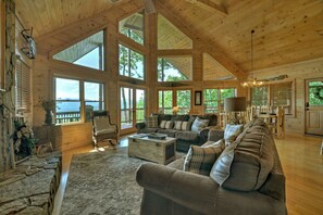 A spacious living room with large windows, a fireplace, and a stone wall. - Eagle Ridge, is pet-friendly haven with a full fenced area and offers awe-inspiring mountain views, a bubbling hot tub, cozy outdoor fireplace, and reliable WiFi. (Mineral Bluff)