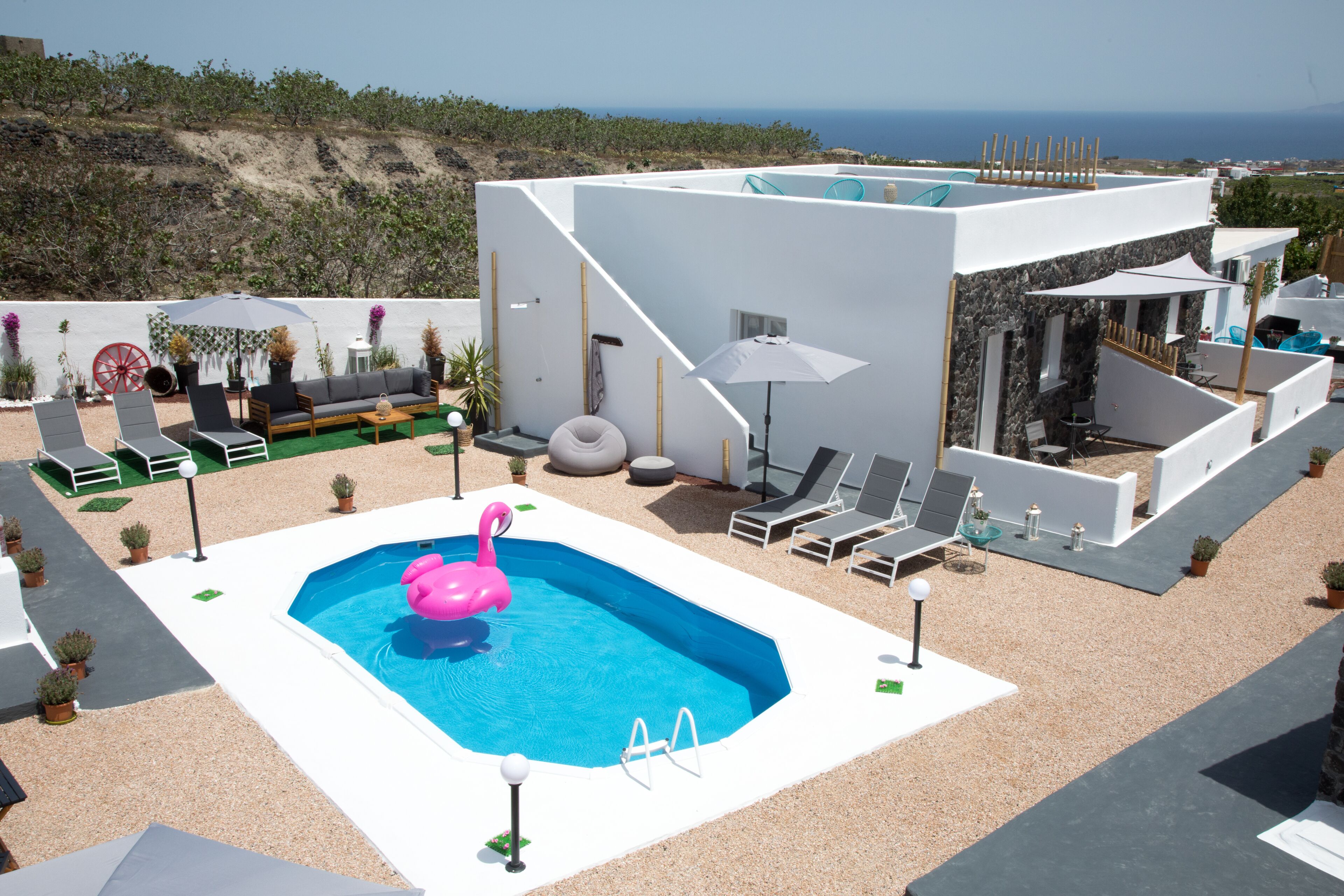 Un espace piscine extérieur moderne, agrémenté d’un flotteur en forme de flamant rose, de chaises longues et offrant une vue sur la mer.