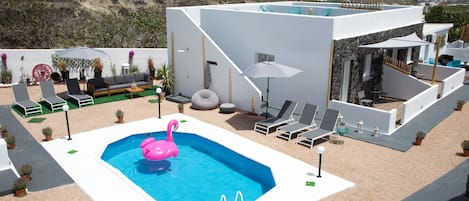 Un espace piscine extérieur moderne, agrémenté d’un flotteur en forme de flamant rose, de chaises longues et offrant une vue sur la mer.