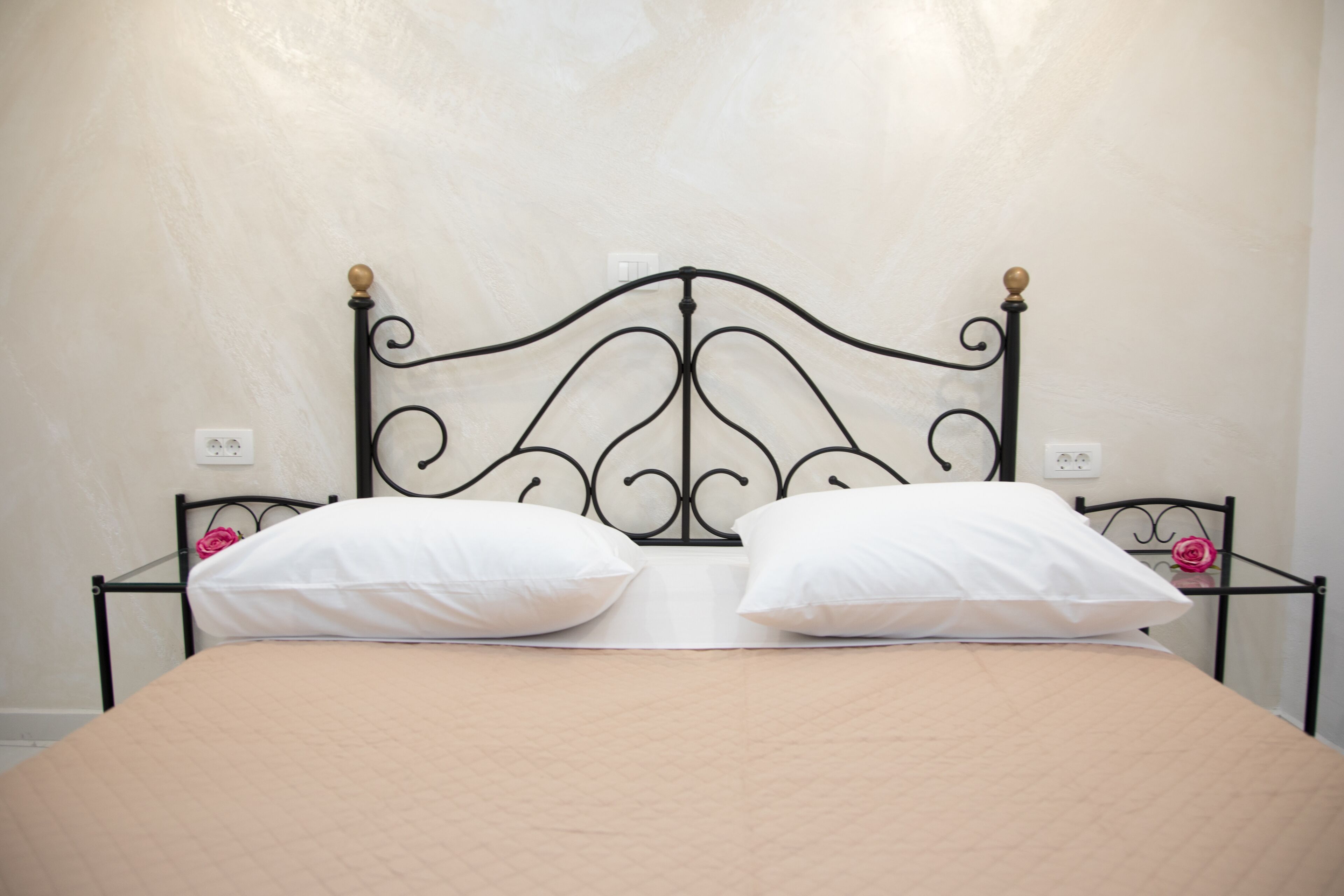 A bed with a headboard, two white pillows, and a beige bedspread.