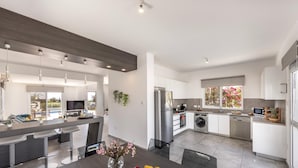 A modern kitchen with a central island, stainless steel appliances, and a dining area with a fruit bowl. - Ayia Napa Bay View Villa 5 (Ayia Napa)