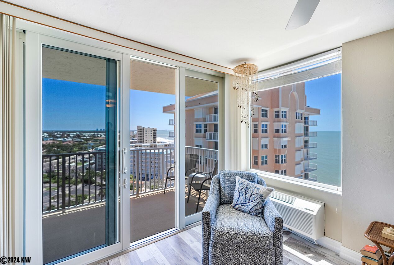 A balcony with a chair, a view of the city, and a building in the background.