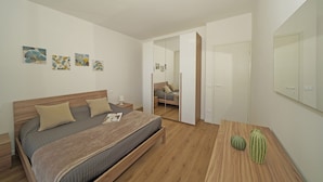 A modern bedroom with a wooden bed, bedside tables, a mirror, and artwork on the wall. - Poggio al Lago 17 by Wonderful Italy (Sirmione)