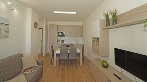 A modern kitchen with a dining area, a flat-screen TV, and a sofa. - Poggio al Lago 17 by Wonderful Italy (Sirmione)