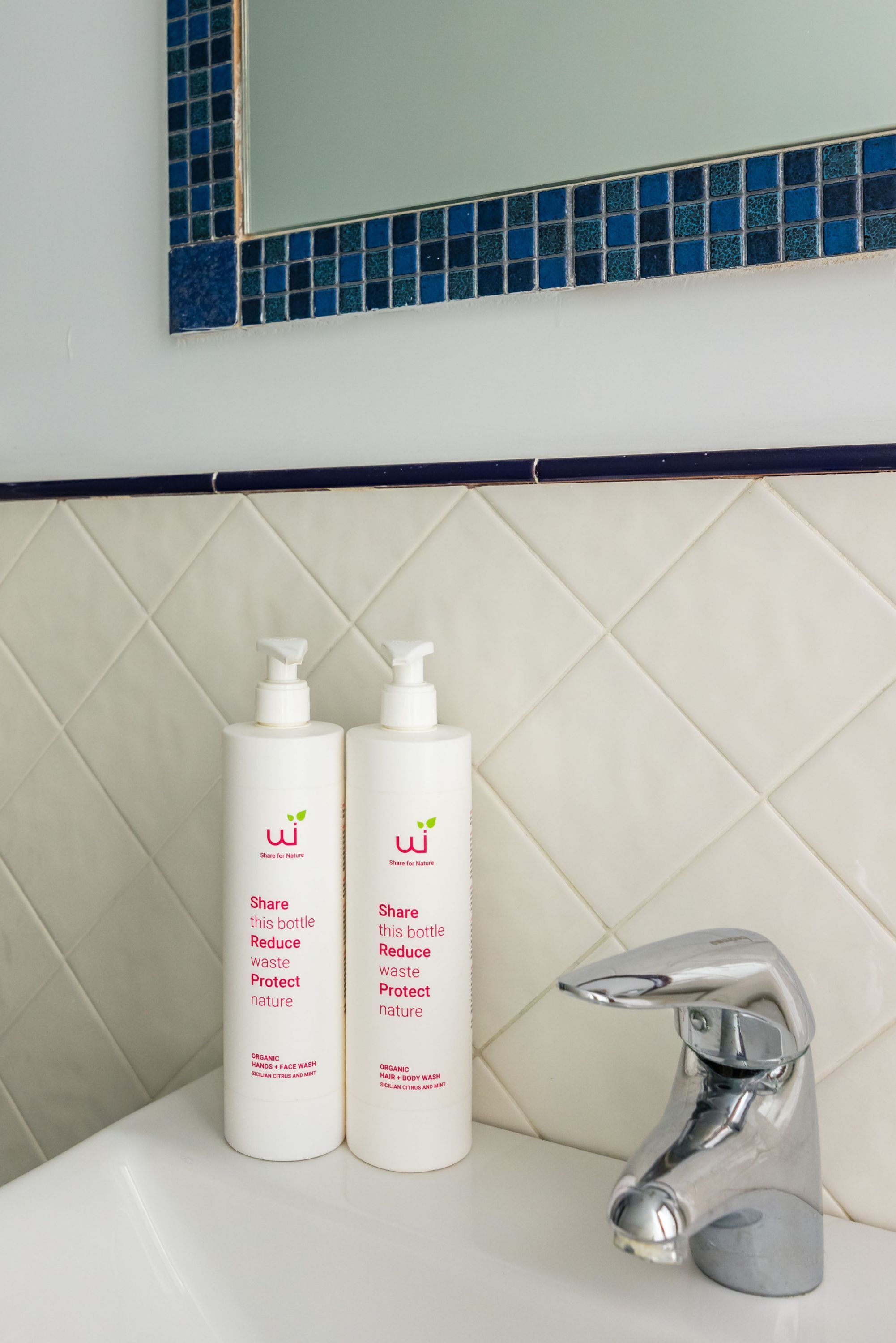 A bathroom with two white bottles labeled "Share for Nature" and a chrome faucet.