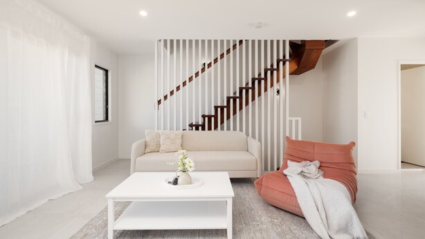 A modern living room with a staircase, a white sofa, a red armchair, and a coffee table. - Netflix, Brand new 4BR,Fast NBN,AC, Free Parking (Southport)