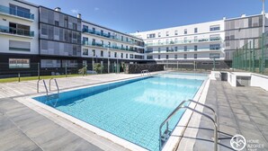 A modern apartment complex with a swimming pool, multiple balconies, and a clear sky. - Home Azores - Pico do Salomão Poolside Retreat (Ponta Delgada)