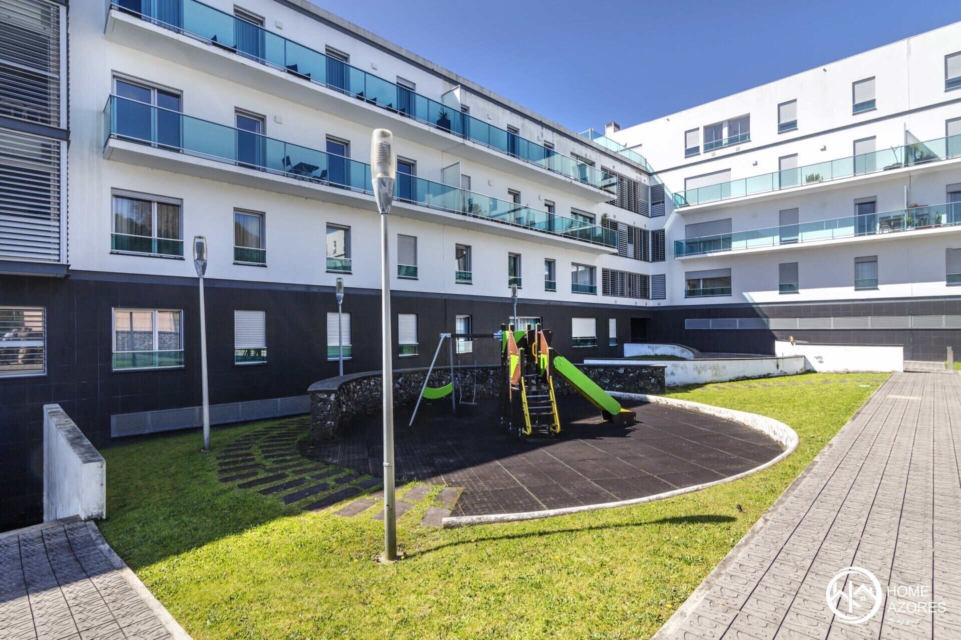 A modern apartment building with a rooftop playground, including slides and climbing structures.