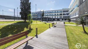 A modern building with a covered outdoor area, a wooden walkway, and a fenced perimeter. - Home Azores - Pico do Salomão Poolside Retreat (Ponta Delgada)
