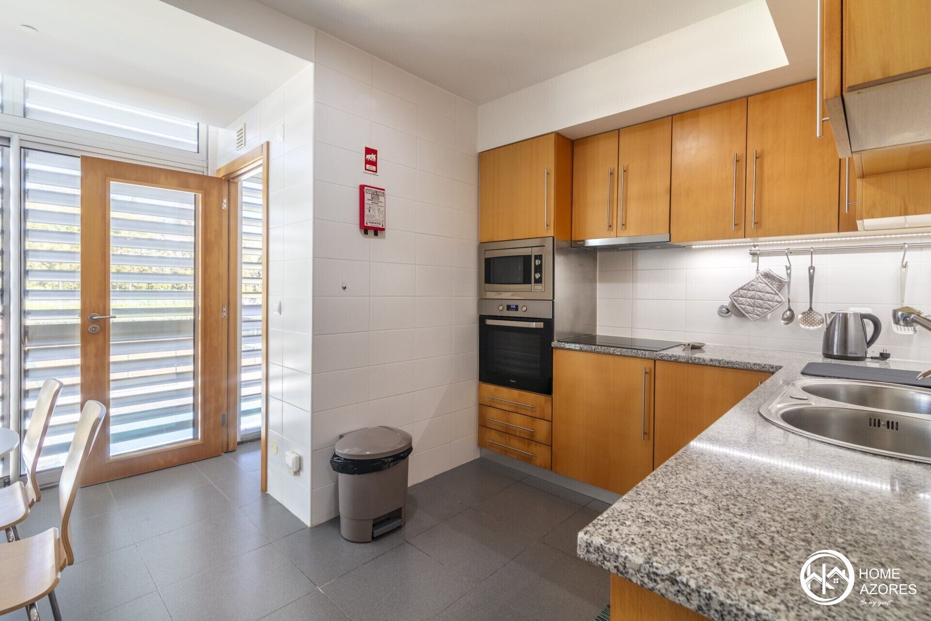 A modern kitchen with wooden cabinets, a stainless steel sink, and a microwave.