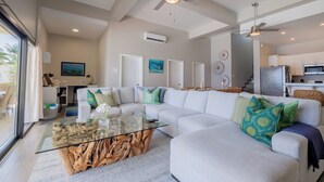 Una sala de estar moderna con una mesa de centro de vidrio, sofás blancos y cojines decorativos.