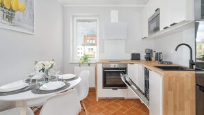 A compact kitchen with white cabinets, a built-in oven, a microwave, and a sink.