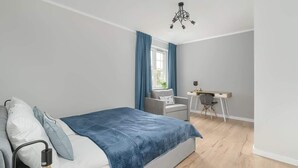 A bedroom with a bed, a desk, and a chair.