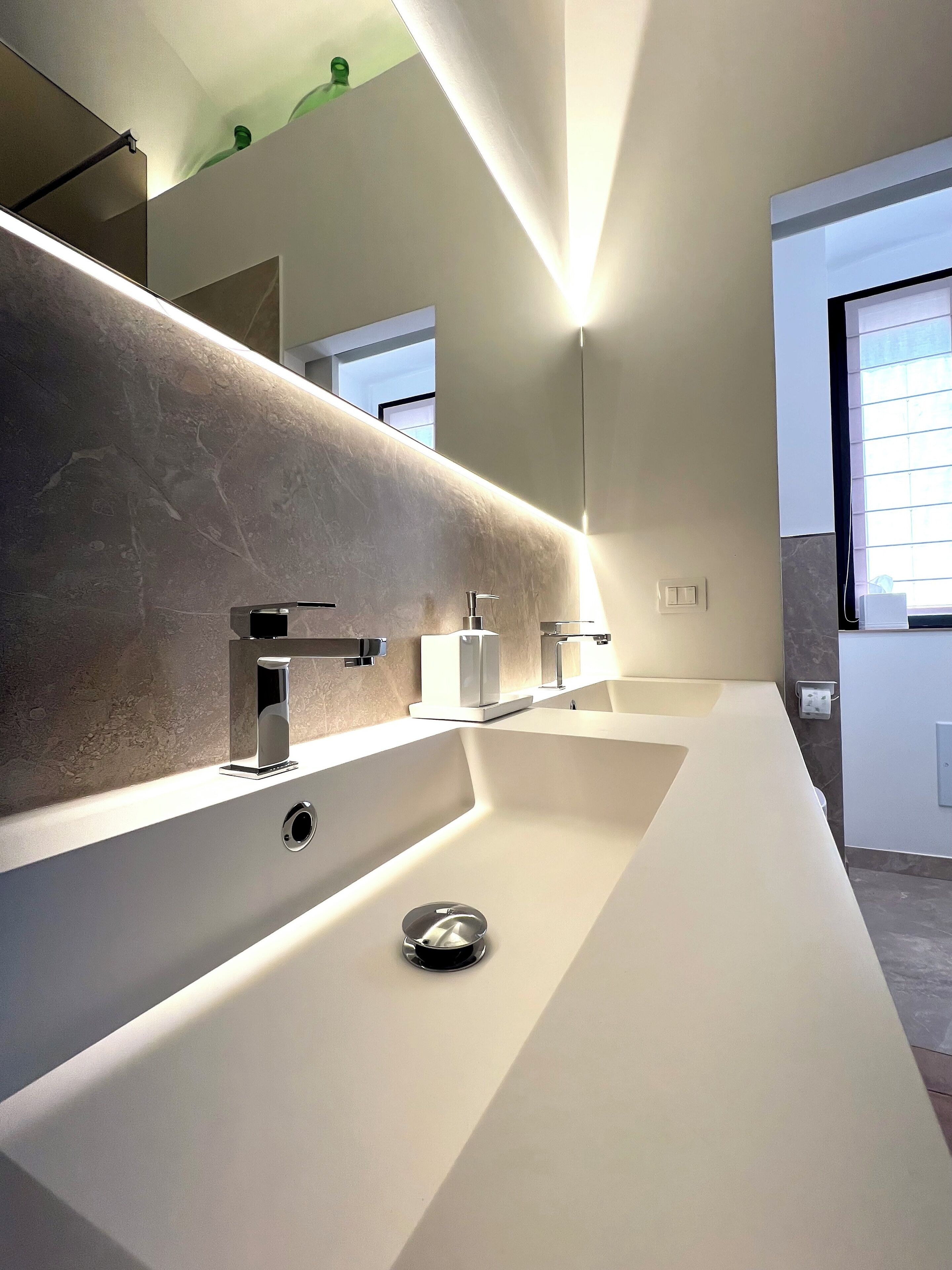 A modern bathroom with a large mirror, a single sink, and a toilet.