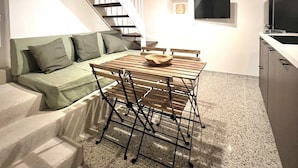 A modern kitchen with a dining table and chairs, a built-in oven, and a TV mounted on the wall. - RESIDENZA ORTENSIA (Petacciato)