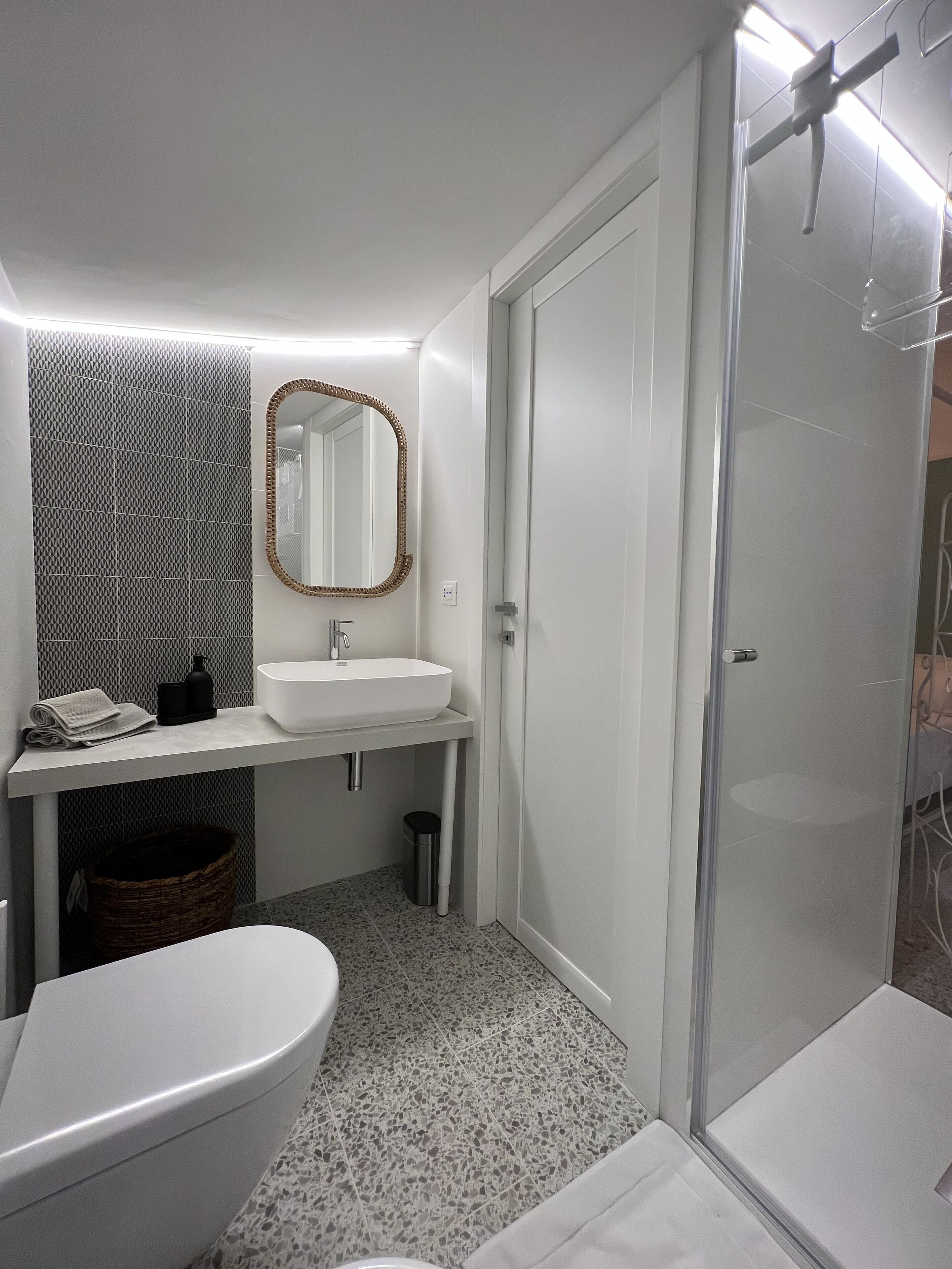 A modern bathroom with a white sink, mirror, and toilet.