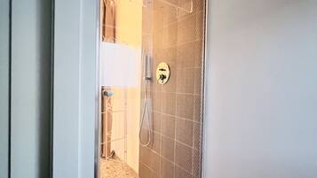 A modern bathroom with a glass shower enclosure, a towel rack, and a visible toilet.