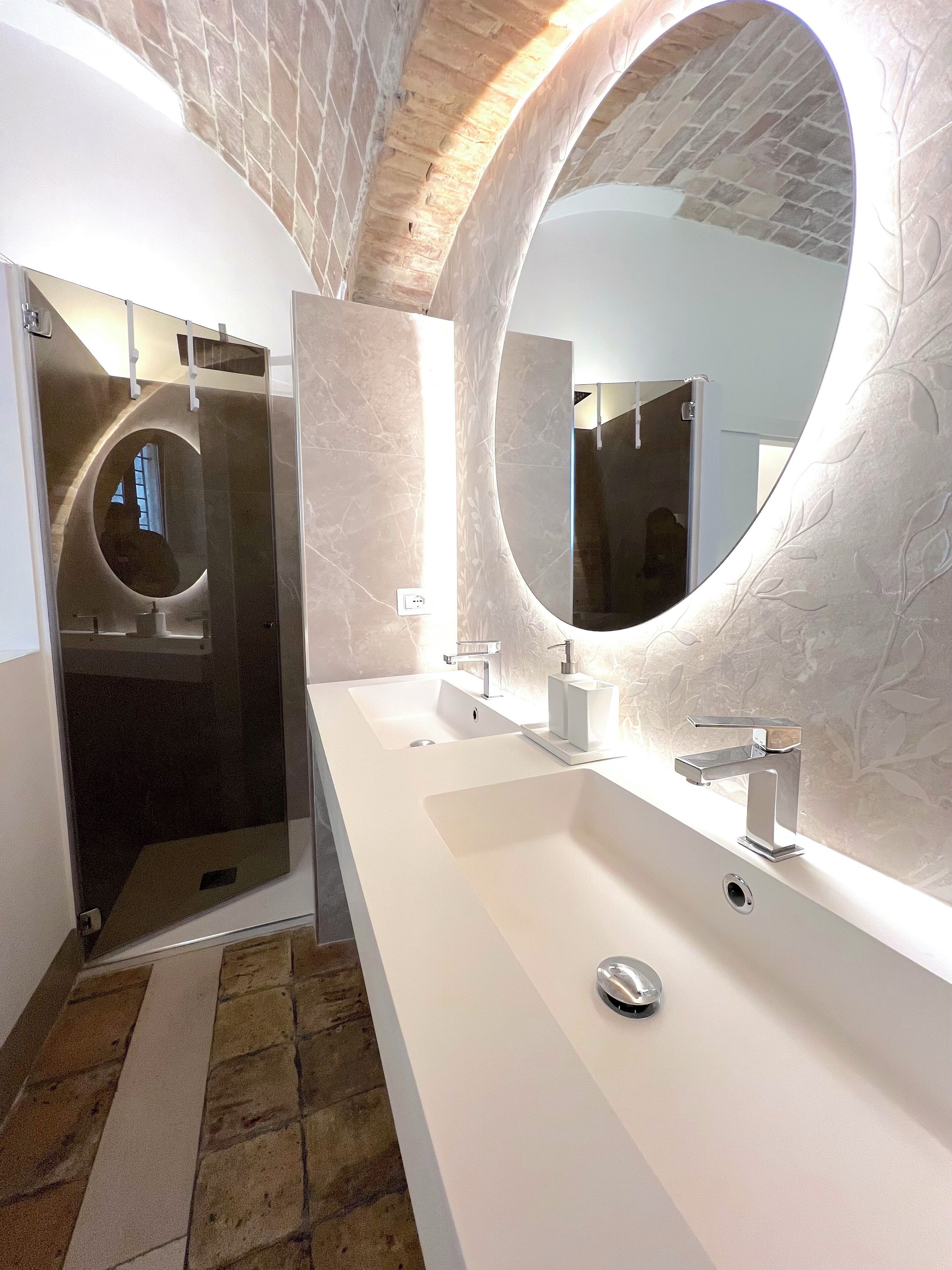 Une salle de bain moderne avec un grand miroir, deux lavabos et une douche.