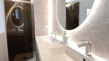 Une salle de bain moderne avec un grand miroir, deux lavabos et une douche.
