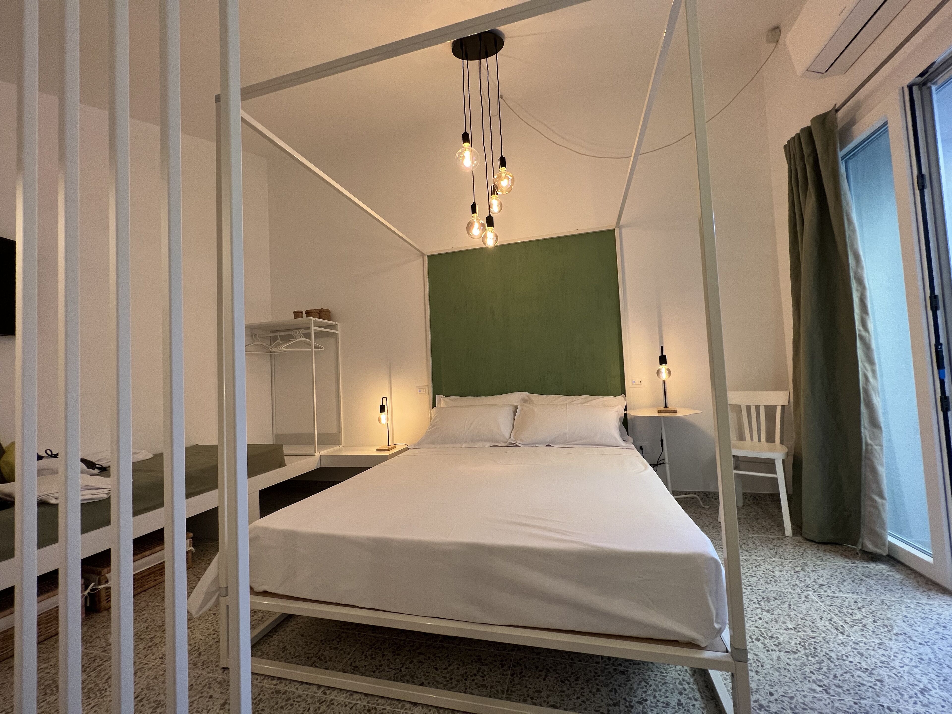 Una moderna camera d'albergo con un letto, comodini, un armadio e una finestra con tende.
