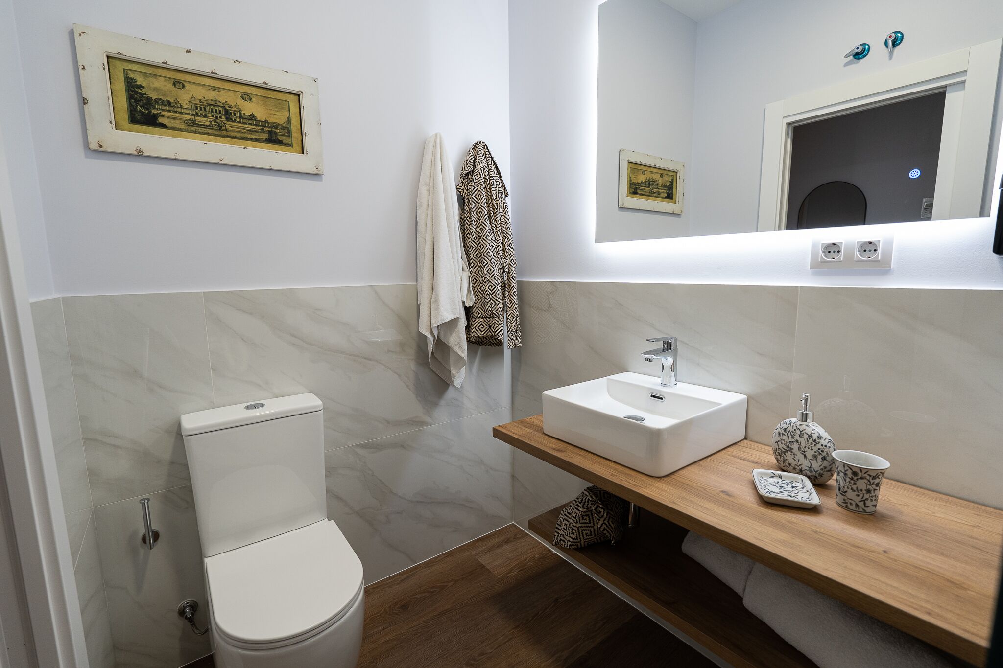 Un baño moderno con inodoro, lavamanos y tocador de madera.