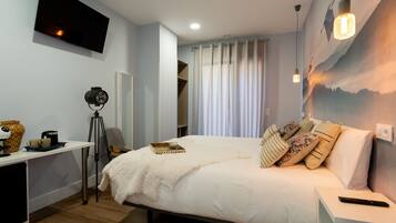 A bedroom with a bed, bedside table, lamp, and a wall-mounted TV.