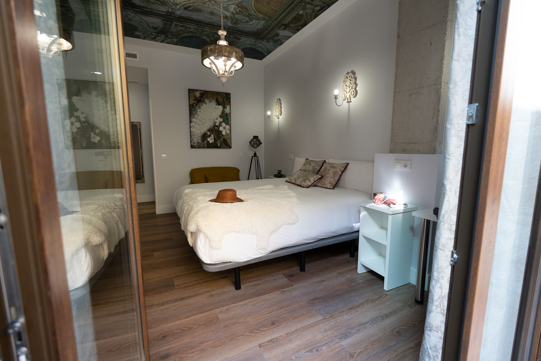 A bedroom with a bed, a bedside table, a lamp, and a ceiling with a decorative design.
