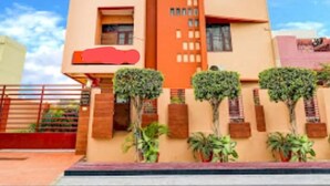Un hotel moderno con fachada color beige, múltiples ventanas y un letrero rojo en la esquina superior derecha.
