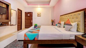 Una habitación de hotel con cama, mesita de noche y televisor en la pared.