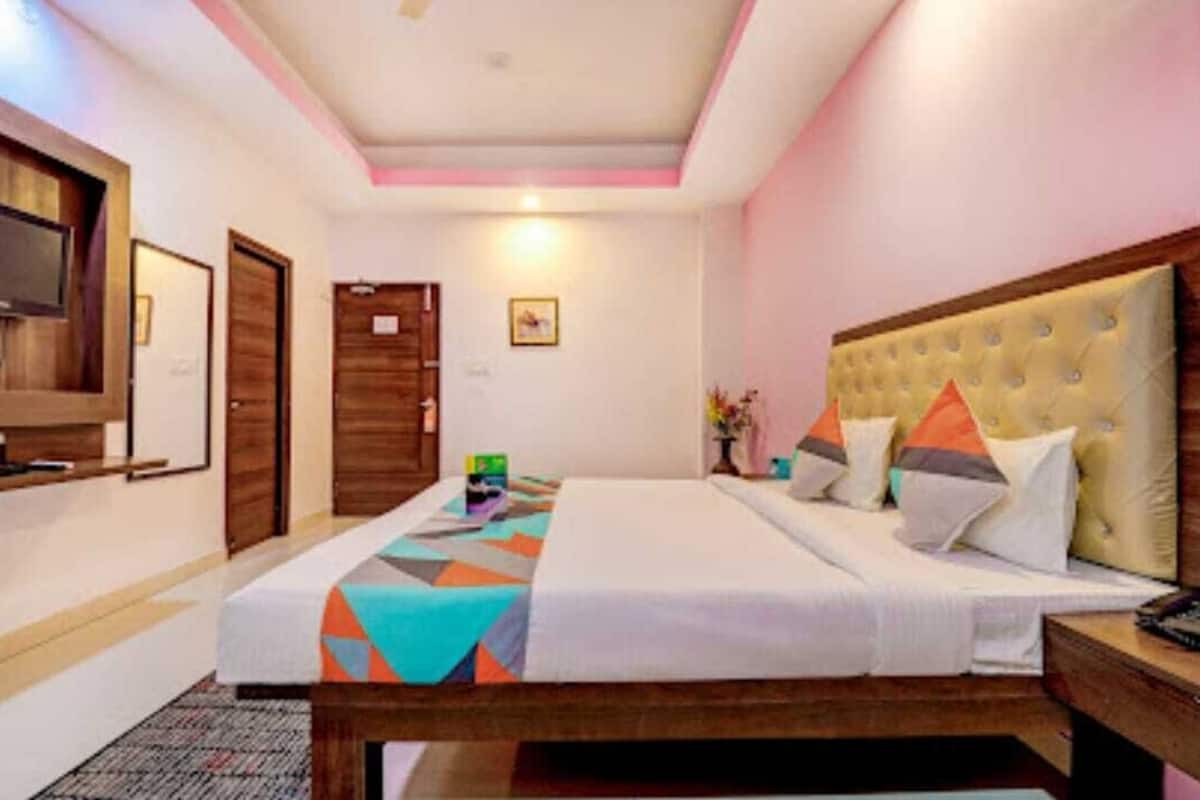 Una habitación de hotel con cama, mesita de noche y televisor en la pared.