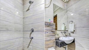 Un baño con paredes de mármol, ducha y lavabo con espejo.