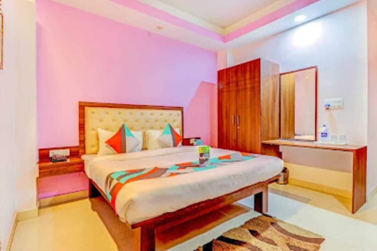 Un dormitorio con cama, mesitas de noche, un armario de madera y un espejo.