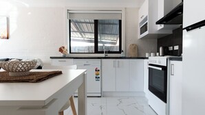 A modern kitchen with white cabinetry, a built-in oven, and a window above the sink. - Riverside Gem with Parking & WiFi (Riverside)