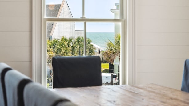 Een kamer met uitzicht op zee, een houten tafel en een stoel.