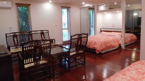 A bedroom with a bed, two chairs, a table, and a mirror. - Elegant Holiday Studio (Werribee)